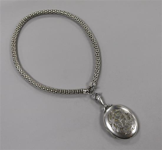 An engraved white metal oval locket decorated with bird and monograms, on a fancy link white metal chain, locket 50mm.